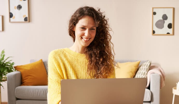 Mujer sonriente utilizando un portátil que está iniciando Norton Safe Search.